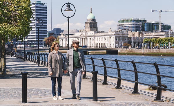 A couple strolls along the Liffey River in the heart of Dublin City, Ireland
